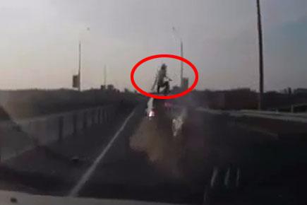 Dramatic escape: Biker somersaults onto moving car during crash