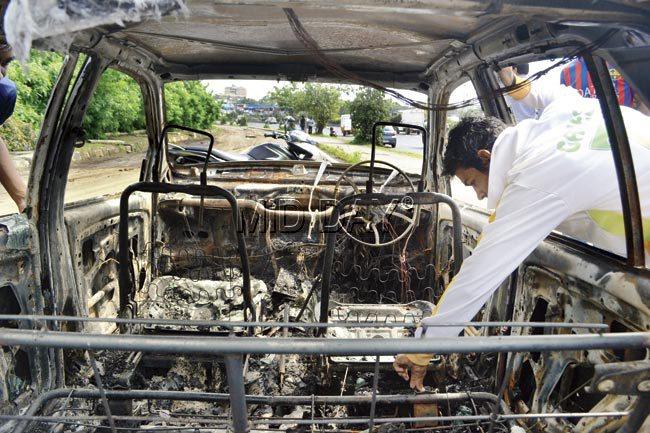 Passers-by inspect the charred remains of the car.  Pics/Datta Kumbhar