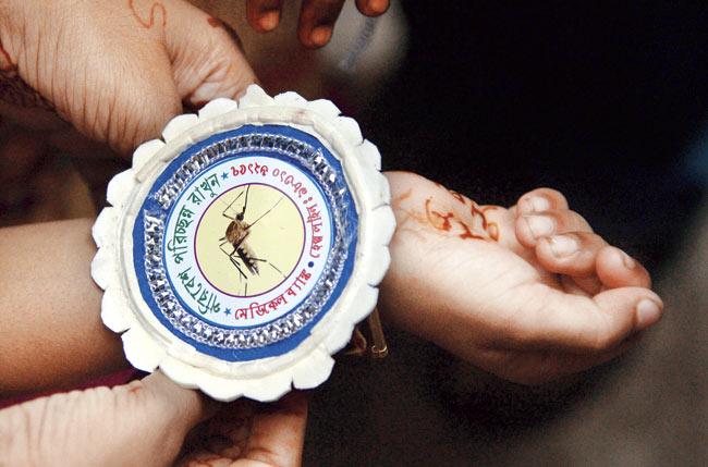A girl ties rakhi around her brother’s wrist with a picture of a mosquito to create awareness about vector-borne disease in Kolkata on Sunday. Pic/AFP