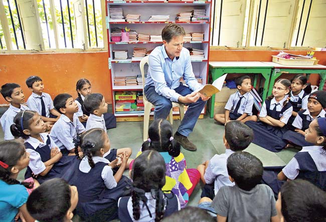 British Deputy Prime Minister Nick Clegg (C) reads to  schoolchildren at the Muktangan school for under-privileged children in Mumbai yesterday. Pic/AFP 