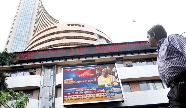 A man watches the share prices ticker at Dalal Street alongside a digital broadcast of Arun Jaitley delivering his Budget speech in Parliament