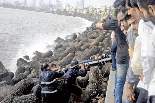 Two boys fell into the water after huge waves lashed Marine Drive. While one of them was rescued, the other died. Fire brigade officers are seen here pulling out the body. File pic