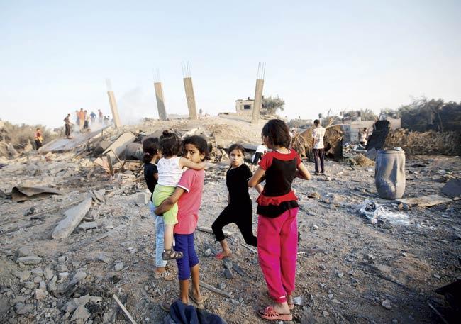 Palestinian children stand by damaged houses after an Israeli missile strike hit Gaza City on July 8. The Israeli air force launched dozens of raids on the Gaza Strip overnight after massive rocket fire from the enclave pounded southern Israel, leaving 17 people injured. Pic/AFP