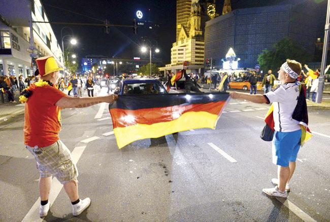 Fans hold a national flag in front of cars near the zoo train station after Germany won the FIFA World Cup 2014