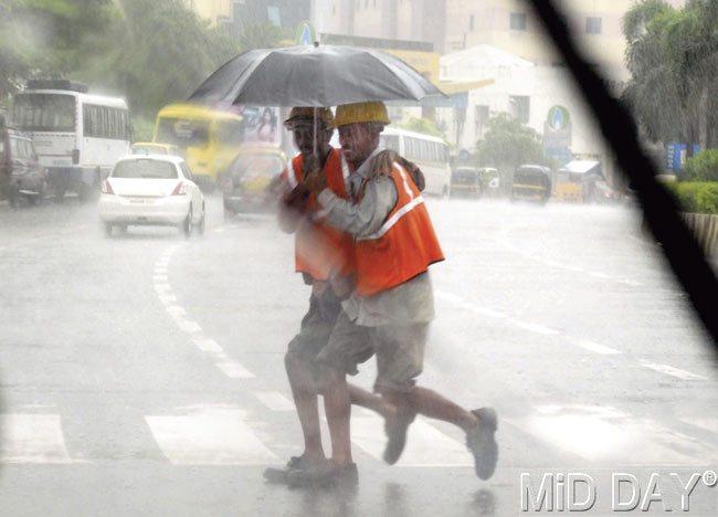 Two workers join hands to make it across the street in Bandra. Pics/Shadab Khan