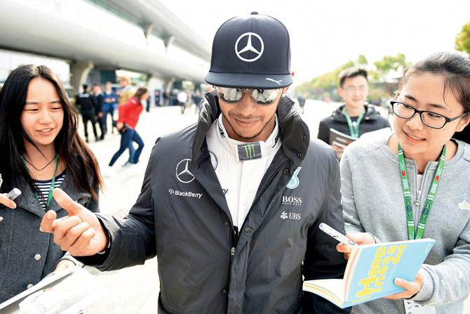 Hamilton signs autographs for fans in the paddock. pic/afp