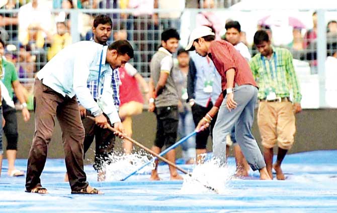 Groundstaff try clear the flooded outfield after heavy rains washed out the IPL match between KKR and RR at Eden Gardens. Pic/PTI