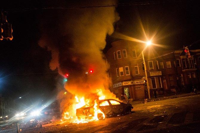 Two cars burn in the middle of an intersection at New Shiloh Baptist Church in Baltimore, Maryland