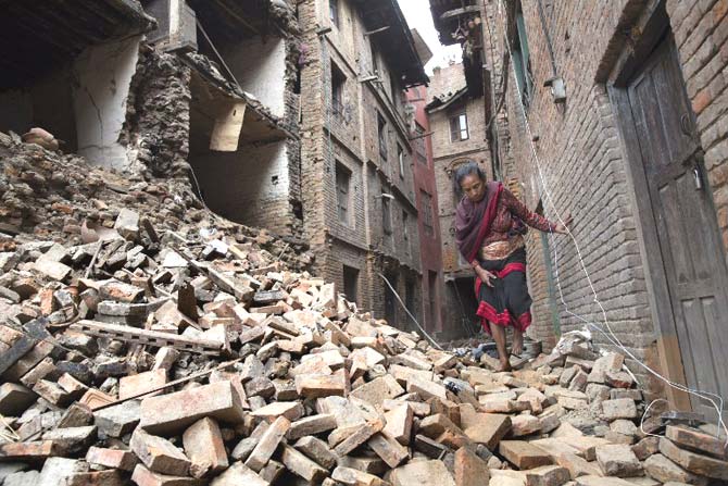 Woman walks past damage in Bhaktapur, near Kathmandu, caused by the 7.8 magnitude earthquake. Pic/AFP