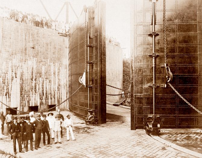 80-Feet Entrance. View Of Back Of Gates And North Culvert Openings — Group of Engineers and Contractors (Victoria Dock Construction, Bombay), by Edward Taurines (February 21, 1888).  British Library, London/© British Library Board. Susan Hapgood points out the way Taurines’ photographic eye commands attention to this engineering marvel and shows the man in white, dwarfed by the mighty gate, standing near the large pile of planks. 