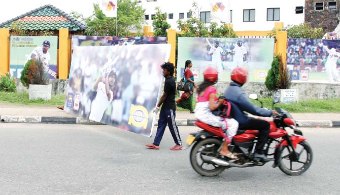Onlookers watch posters of Kumar Sangakkara placed outside the Galle International Stadium yesterday. Pics/Solaris Images