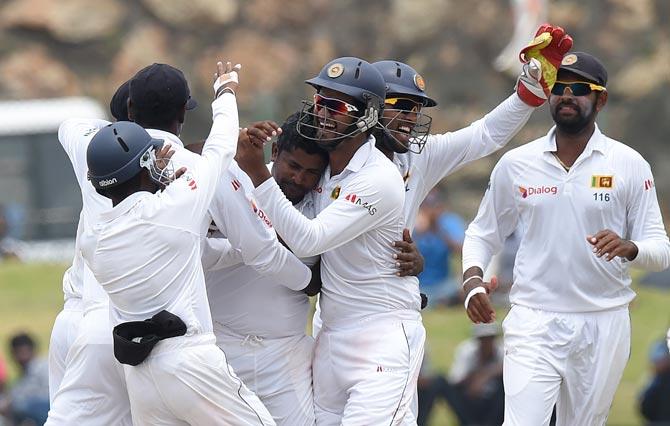 Sri Lankan cricketer Rangana Herath (C) and teammates celebrate after the dismissal of Indian batsman Wriddhiman Saha during the fourth day of the opening Test match between Sri Lanka and India at The Galle International Cricket Stadium in Galle on August 15, 2015