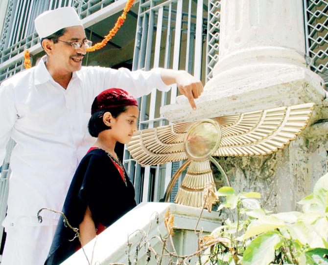 An Indian Parsi priest gestures as he explains the significance of the Asho Farohar (Angel) to a young girl at a Parsi Fire Temple in Ahmedabad, August 10, 2007, on the occasion of Navroz or the Parsi New Year. PIC/AFP