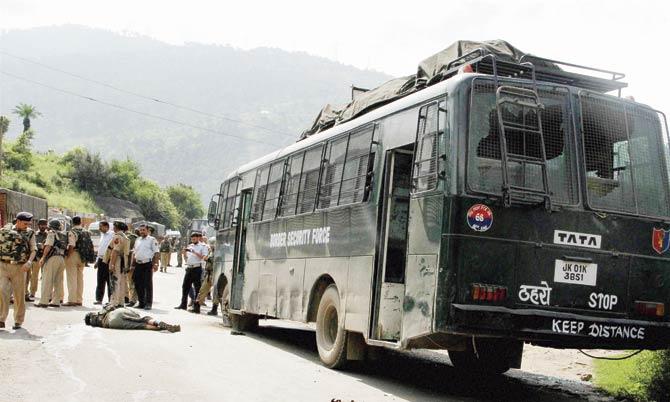 Security persons stand near the dead body of a terrorist who had attacked a BSF convoy on the Jammu-Srinagar national highway in Udhampur district of Jammu and Kashmir yesterday. Pic/PTI