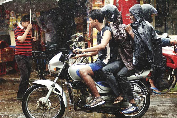 Youths riding triple seat scurry for cover as sporadic showers lashed Thane yesterday morning. Pic/Sameer Markande