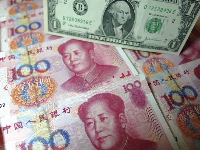 Yuan banknotes and US dollars are seen on a table in Yichang, Central China’s Hubei province as the Chinese currency has the world in a tizzy. Pic/AFP
