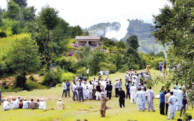 Villagers watch smoke rising from a mortar shell fired by the Pakistani Army near the Line of Control (LoC) in Balakot in Jammu on Sunday. Pic/PTI