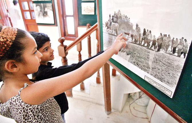 A file picture of Pakistani children looking at a photograph of the Partition at an exhibition in Lahore. Partition was not only about carving up an ancient land into two states, a butchery committed with knives sharpened on the whetstone of political deceit, it was also about “history’s largest migration”. Pic/AFP 