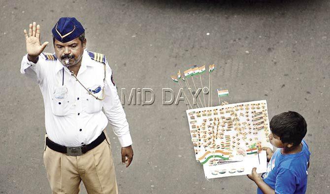 A traffic policeman is at work as a boy sells flags at the signal in South Mumbai. Pic/Bipin Kokate