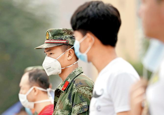 Volunteers and paramilitary soldiers wearing masks stand guard outside a temporary shelter after the explosions in Tianjin.