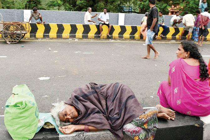 Homeless: An old woman rests on the kerbstone after being rescued from a flooded locality in rain-hit Chennai. Pic/PTI