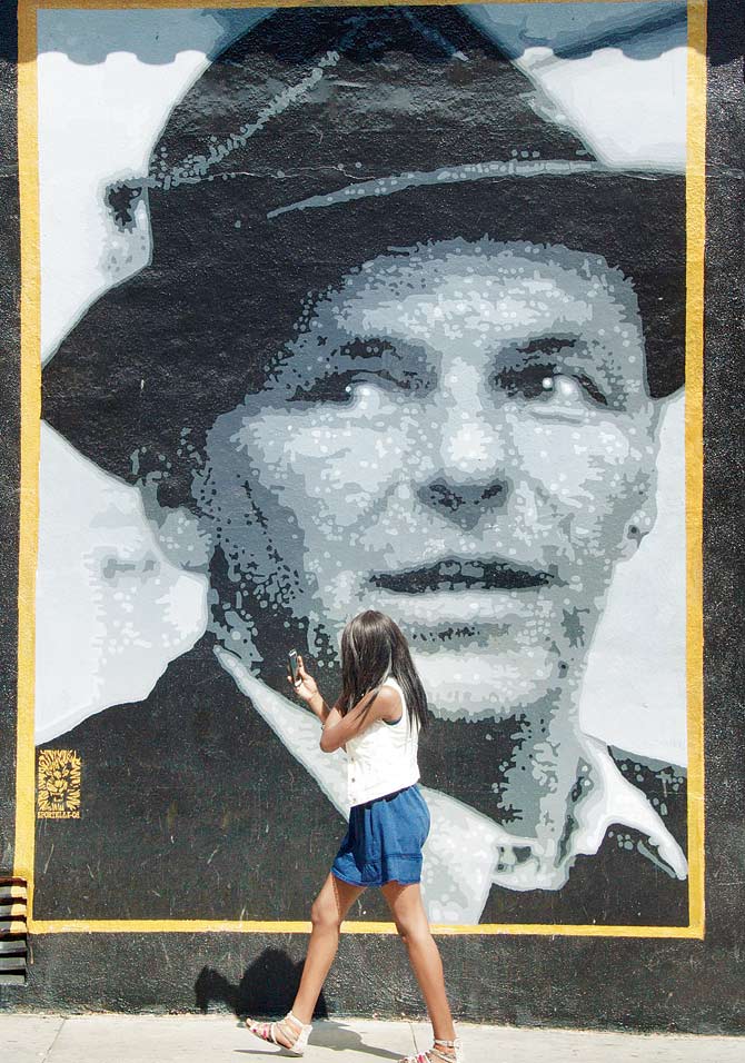 A woman walks by a street painting of Frank Sinatra in Hollywood on August 15, 2013 in  Los Angeles, California. PIC/AFP