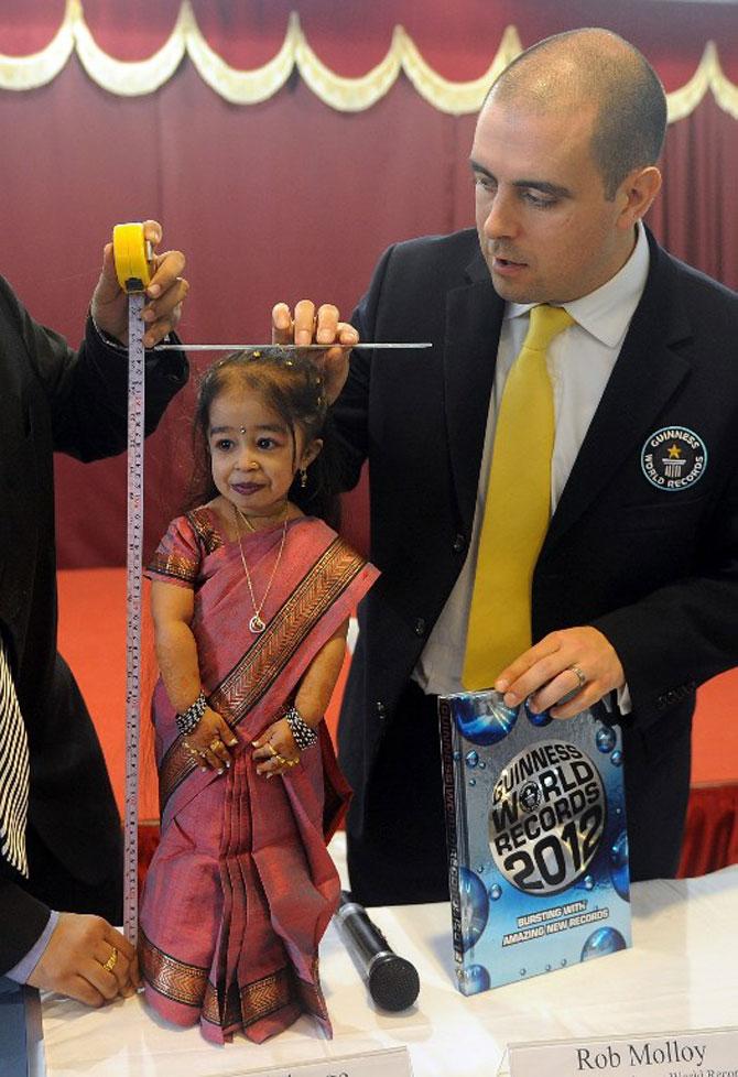 Guinness World Records adjudicator Rob Molloy (R) measures Jyoti Amge during a news conference in Nagpur on December 16, 2011. Amge was officially announced by the Guinness World Records on December 16 the world