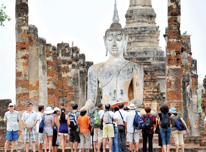 A picture taken on March 15, 2011, in Sukhothai, 600 km northern Bangkok, shows tourists gathering in front of a statue of the Buddha. PIC/ AFP