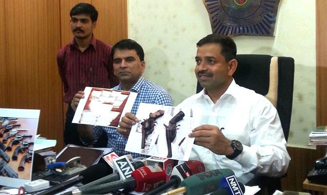 DCP Kulkarni and Sr PI Vast showing pictures of photos seized from accused Santosh Khanvilkar