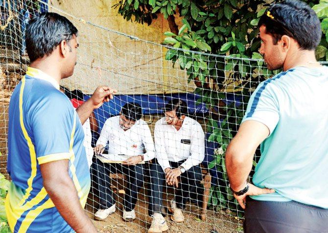 Umpires (seated) prepare a report after calling off play at Cross Maidan. Pic/Satej Shinde