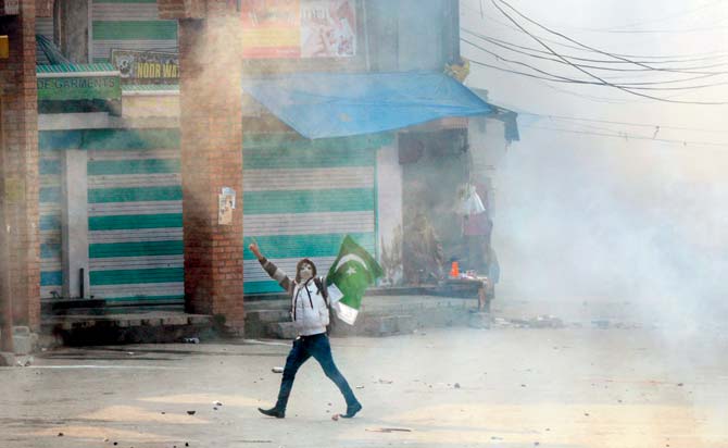 A Kashmiri protestor holds a Pakistani flag as he shouts pro-independence slogans, after Indian police fired smoke shells during clashes with Kashmiri protestors in Srinagar on Friday. Pic/AFP Photo