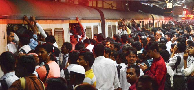 People hold on to valigators as they board a train at Dadar. File pic