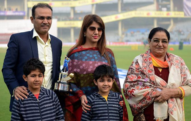  Virender Sehwag (L) holds his trophy from the Board of Control for Cricket in India (BCCI) as he poses with his family after a felicitation ceremony