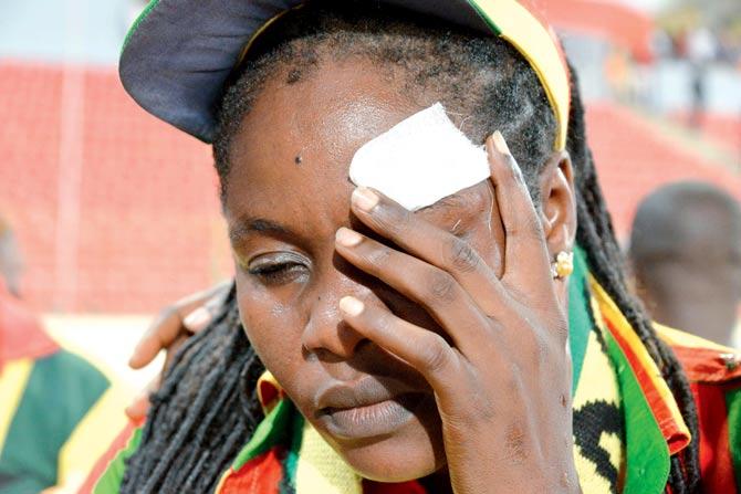 A Ghana supporter holds her face afteR being hit by an object. PICS/AFP