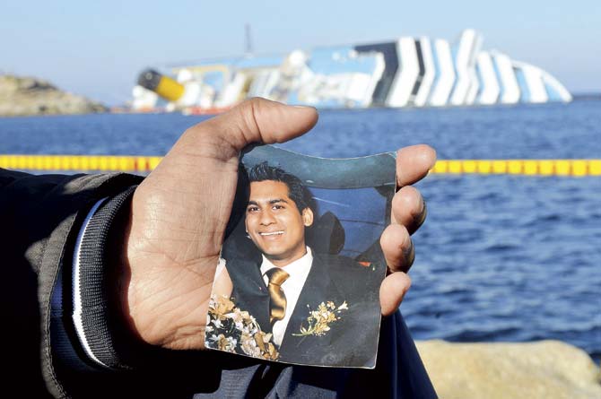 Kevin Rebello shows a picture of his brother Russel near the stricken ship Costa Concordia. File pic