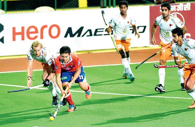A Dabang Mumbai player (red jersey) is tracked by Kalinga Lancers players during their Hockey India League match at the MHA-Mahindra Stadium, Churchgate yesterday. Pic/PTI