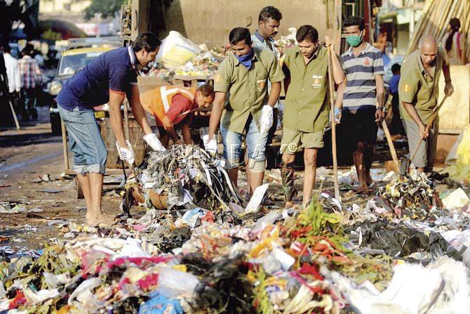 BMC conservancy workers use plastic bags as gloves to clean garbage at Byculla. Pic/Bipin Kokate
