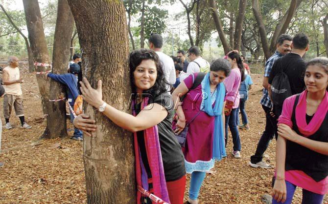 A woman hugs a tree as she participates in a Chipko protest to save Aarey