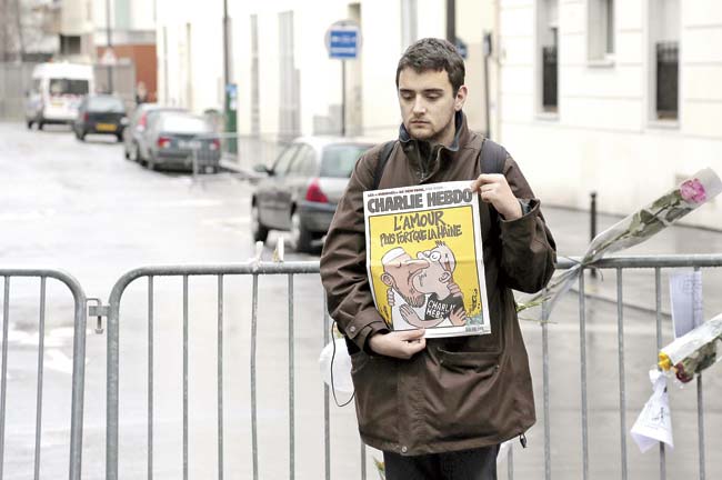 A man holds up a copy of the satirical newspaper Charlie Hebdo reading ‘Love stronger than hate’ in tribute, after gunmen attacked the weekly publication’s Paris office and killed 12 people. Pic/AFP