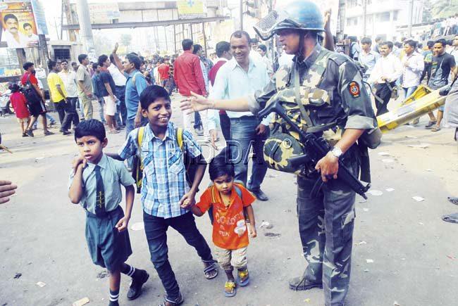 Saving the tiny tots: While his colleagues were busy controlling riots and targeting some innocent passengers in the process, this official was seen escorting children safely out of Diva station. Pic/Sameer Markande