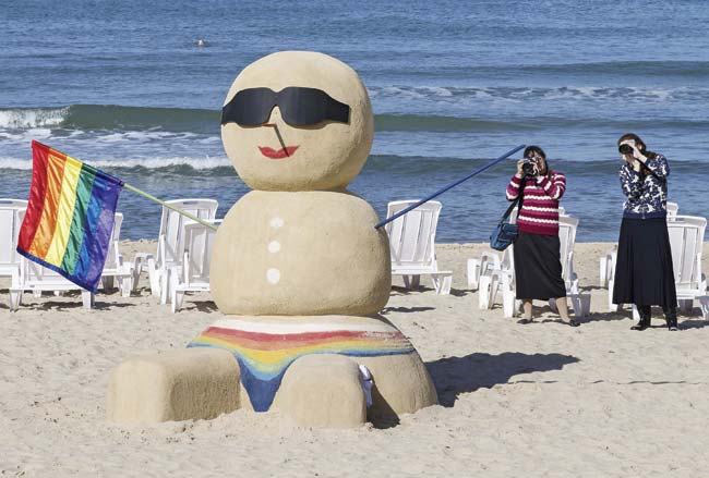 Women take pictures of a sand sculpture of a snowman holding a rainbow gay pride flag at a beach in Tel Aviv, Israel. The ‘Snowman’ marked the start of a two week Gay Winter Festival that will end on January 7, 2015. pic/AFP