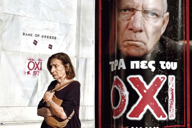 A woman passes by the headquarters of Bank of Greece daubed with the word ‘NO’ and a poster with a portrait of German Finance Minister Wolfgang Schaeuble that reads ‘Now tell him NO’. Pics/AFP