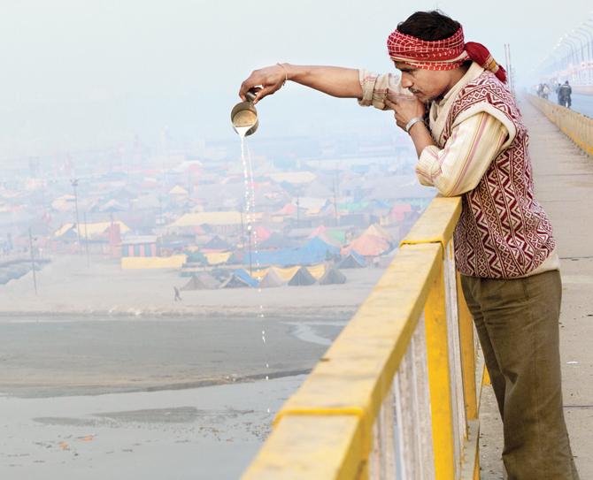 A milkman pours a litre of milk into the Ganga from atop the Shastri bridge before he begins his day’s delivery to his customers (Volume 7: Faith, Fate, Worship)