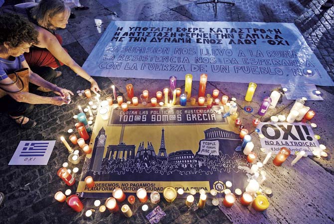 People light candles displayed next to a message as they take part in a demonstration in support of Greece, at Sant Jaume square in Barcelona, Spain