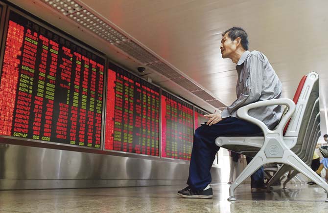 An investor looks at a board showing stock market movements at a securities company in Beijing as Chinese stocks surged for a second day on July 10 as a government rescue plan offered a respite from a month-long rout.  Analysts warned of further uncertainty and volatility ahead. Pics/AFP