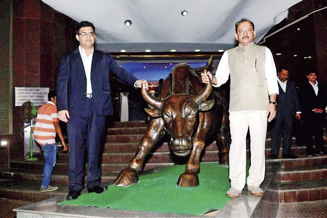 Dhruv Agrawal (r), Director, Manpasand Beverages Ltd poses with the bull statue at the listing of the company at Bombay Stock Exchange in Mumbai. Pic/PTI