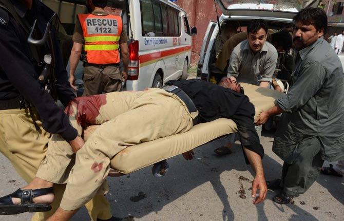 Pakistani men carry an injured policeman into a hospital after two suicide bomb attacks on a Church in Peshawar on September 22, 2013. Two suicide bombers killed at least 53 people and wounded more than 100 in an attack on a church service in the restive northwestern Pakistani city of Peshawar, officials said.