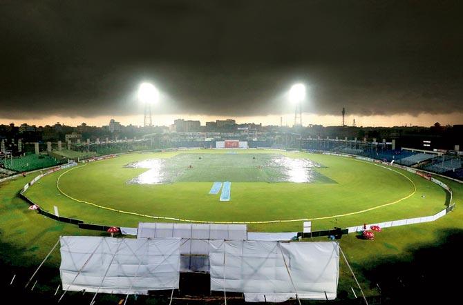 Such a dampener: Bangladeshi groundstaff cover the playing field as rain stops play during the opening day of the first Test between Bangladesh and India at Fatullah yesterday. Pic/AFP 