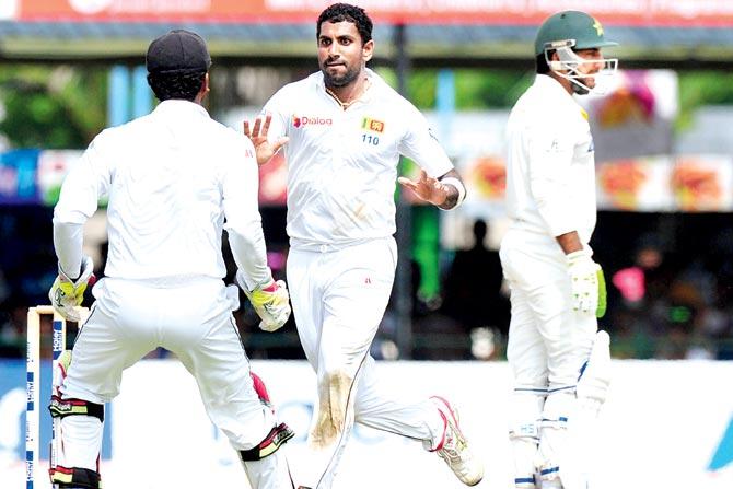 Dhammika Prasad (right) celebrates a wicket yesterday