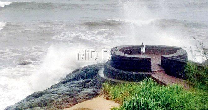 A man enjoys the waves standing on the bastion of Fort Bekal 